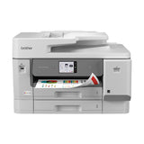 A Brother all-in-one office printer in light gray and dark gray, shown from a front three-quarter angle on a solid white background. A sheet of paper with a multicolor pattern is visible in the output tray.